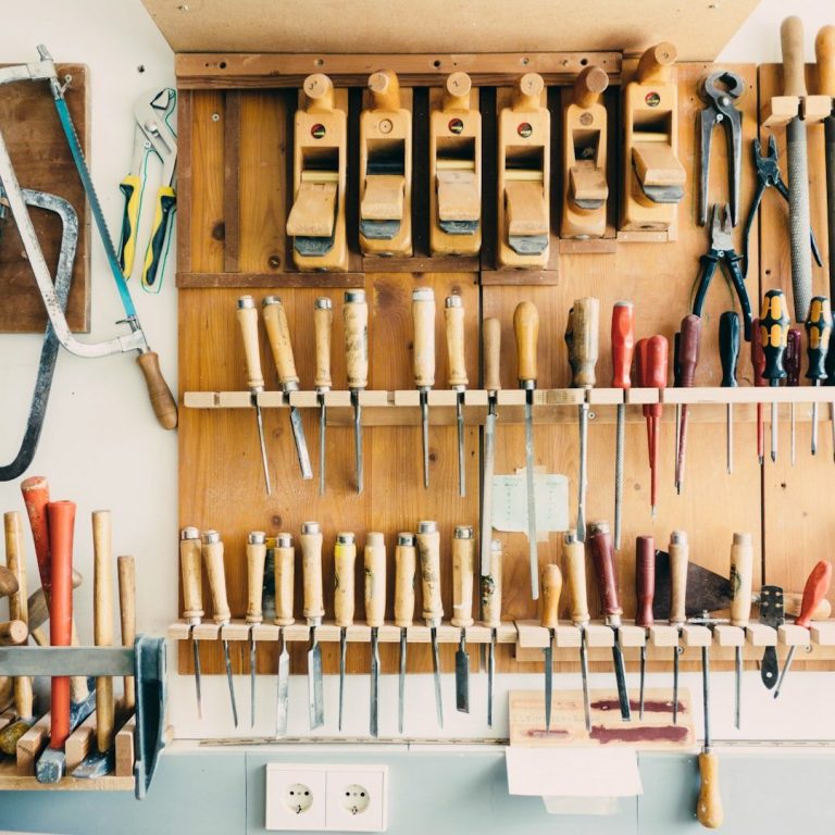 A wooden wall with various hand tools and clamps neatly arranged.