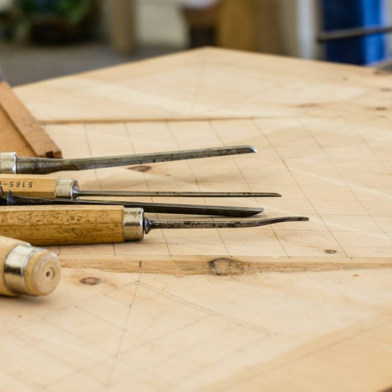 A collection of carving tools resting on a wooden surface.